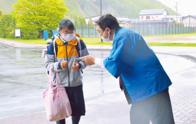 写真：登校する生徒に啓発物を手渡す小笠原市長