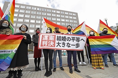 写真：同性婚訴訟の札幌地裁判決後、「違憲判決」と書かれた紙を掲げる原告の弁護士と支援者ら＝２０２１年３月、札幌市