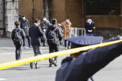 写真：警察官（手前）が警戒する中、試験会場に向かう受験生ら＝１５日午後、東京都文京区の東大