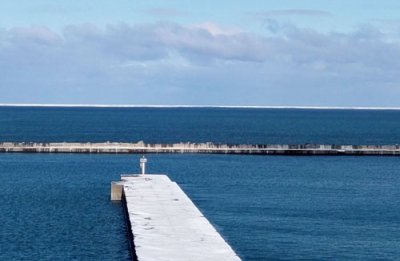写真：紋別市沖に確認された流氷。水平線上にうっすらと見える＝２０日午前（紋別市提供）
