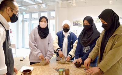 写真：講師から抹茶のたて方を習うマレーシアからの留学生たち