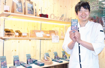 写真：店舗内にできた販売スペース前でチョコレートを手にする谷藤さん