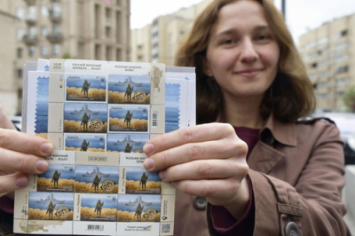 写真：限定発売された記念切手を持つ女性＝２３日、ウクライナ・キーウ（共同）