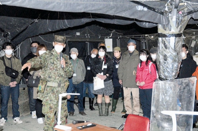 写真：宿営地で隊員から指揮所などの説明を受ける参加者