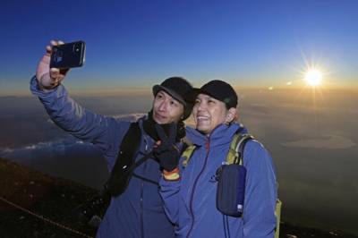 写真：山開きを迎えた富士山の山頂で、御来光と記念撮影する登山者＝１日午前