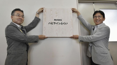 写真：新社名の看板を設置する福井県の杉本達治知事（左）ら＝４日午前、福井市