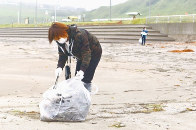 写真：イタンキ浜で流木や海藻などを拾うおかんの会の会員