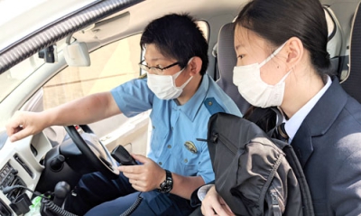 写真：実際にパトカーに乗車し無線の使い方を教わる岡崎さん（右）