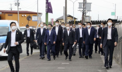 写真：安倍元首相の銃撃事件後、訪問先の福島県浪江町で警護を受ける松野官房長官（奥左から３人目）ら＝７月１６日