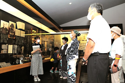 写真：展示を前に堂々と解説する千葉さん（左）