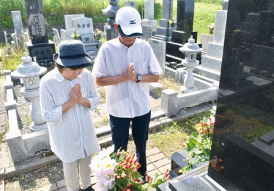 写真：墓前で手を合わせて先祖を供養する夫婦＝１３日午前８時３５分ごろ、室蘭市望洋台霊園