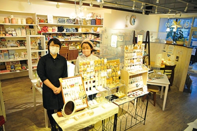 写真：店内では女性に人気の雑貨を販売。「多くの来店を待ってます」とＰＲする田中代表（右）と中島代表