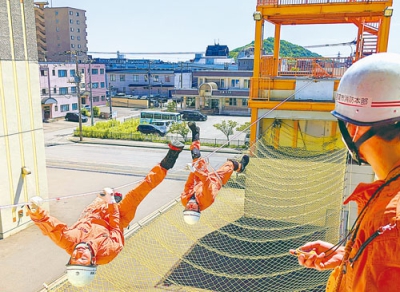 写真：高所に結んだロープを渡るロープブリッジ救出訓練中の隊員