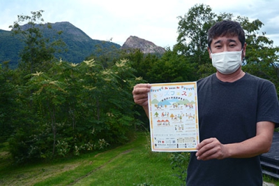 写真：昭和新山などが望める会場でチラシを手にイベントをアピールする石垣さん