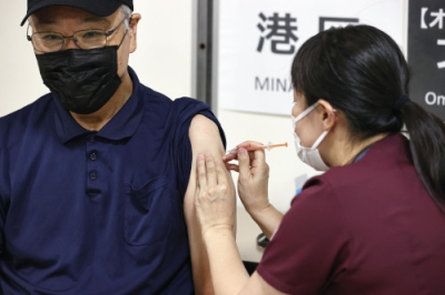 写真：新型コロナウイルスのオミクロン株に対応するワクチン接種を受ける男性（左）＝２０日午前、東京都港区