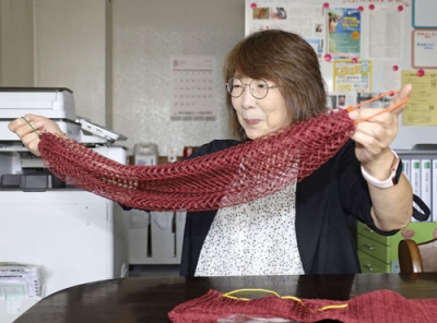 写真：漁網で製作した「くしろ魚網ボディタオル」を手にする森崎三記子さん＝８月、釧路市