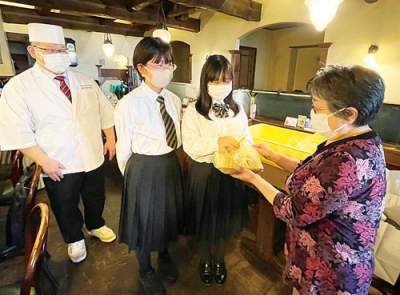 写真：自ら開発した「のぼくま弁当」を手渡す生徒ら