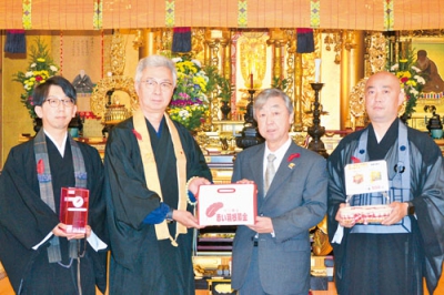 写真：長谷川会長に善意を手渡す日笠住職（左から２人目）ら