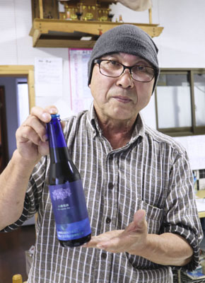 写真：今春発売したヤマブドウ１００％の赤ワインを手にする佐々木真萌さん＝１１月３日、青森県大間町