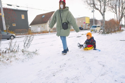 写真：雪が降りそりで遊ぶ親子＝１日午前、室蘭市八丁平