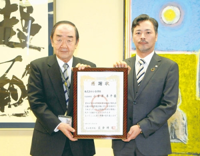 写真：岩倉市長から感謝状を受け取る小金澤代表取締役（右）