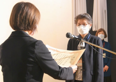 写真：菊地会長から表彰状を手渡される委員