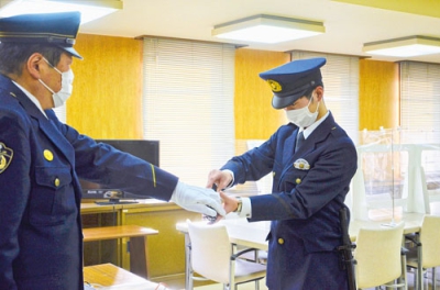 写真：署長から拳銃を貸与される新人警察官（右）