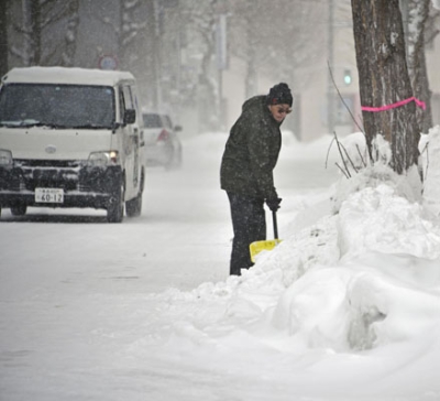 写真：歩道に積もった雪をかく人＝２４日午前１０時２５分、青森市