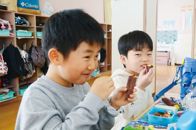 写真：サツマイモを食べて笑顔を見せる京王幼稚園の園児