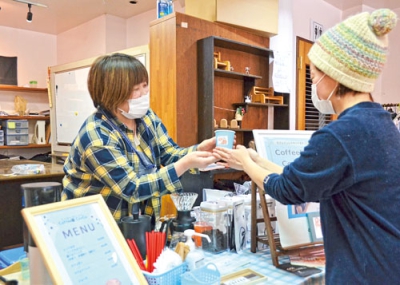 写真：こだわりのコーヒーを来店客に提供する田村さん（左）