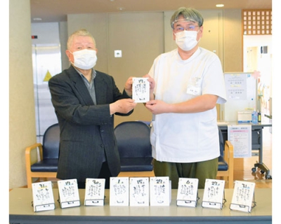 写真：日めくりカレンダーを手にする田中さん（左）と佐藤施設長