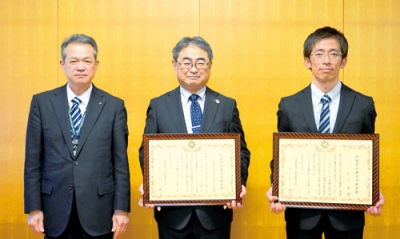 写真：表彰状を受け取った保格校長（中央）と宮川教諭（右）