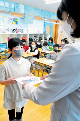写真：担任教諭から通知表を受け取る児童＝みなと小学校