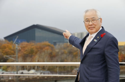 写真：エスコンフィールド北海道を背景に写真に納まる、北広島市の上野正三市長