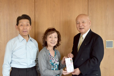 写真：社協の山中会長に寄付金を手渡す日沼さん（中央）。左は斉藤会長