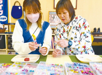 写真：ボールペンに色とりどりのビーズを飾り付ける参加者