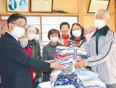 写真：清拭布を寄贈する川村会長（右）と長生会メンバー。左は社協の高木事務局長