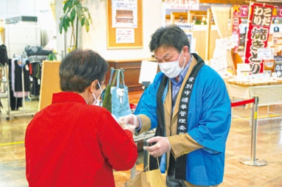 写真：買い物客に啓発物を手渡す関係者
