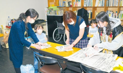 写真：新聞紙でかぶとをを作る「こどもの日イベント」の参加者
