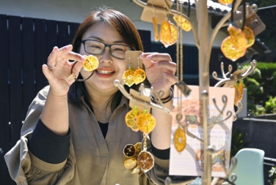 写真：「摘果ミカン」のアクセサリーを手にする藤弘真理子さん＝５月２日、山口県光市