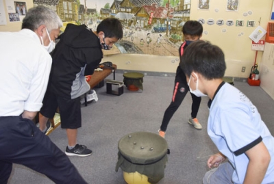 写真：ベーゴマを戦わせる井出祐史さん（左端）と子どもたち＝５月１０日、埼玉県川口市