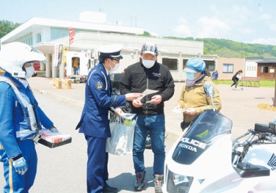 写真：ライダーに啓発品を配布し、交通事故防止を呼びかける警察官