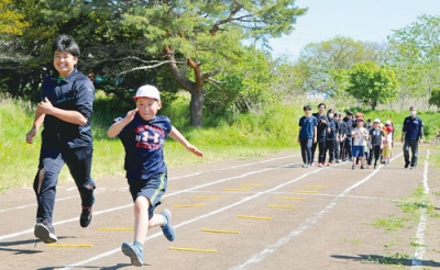 写真：高校生と並走して走るコツを学ぶ関内小児童たち
