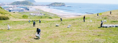 写真：イタンキ浜が一望できる潮見公園内の丘陵地で草刈りを行う参加者