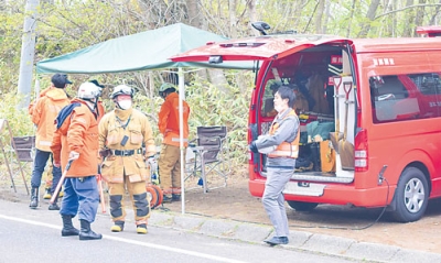 写真：山菜採りの行方不明者を捜索する消防隊員ら