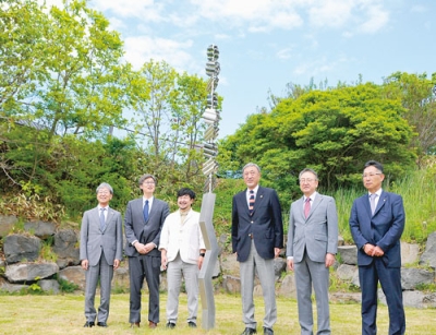 写真：ホタテ貝のモニュメントの前で記念撮影する渡辺さん（左から３番目）や須藤さん（右から３番目）