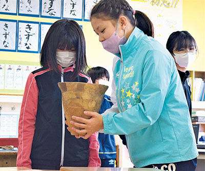 写真：縄文出前講座で土器に触れる幌別小の児童