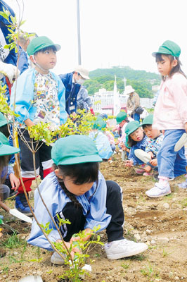 写真：ツツジの苗木に土をかける参加者たち