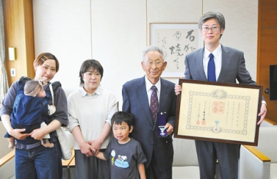 写真：堀井市長から叙勲の伝達を受ける村重さん（右から２人目）
