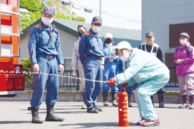 写真：３年ぶりに開かれた小橋内町会の防災訓練で、消火器の使い方を学ぶ参加者